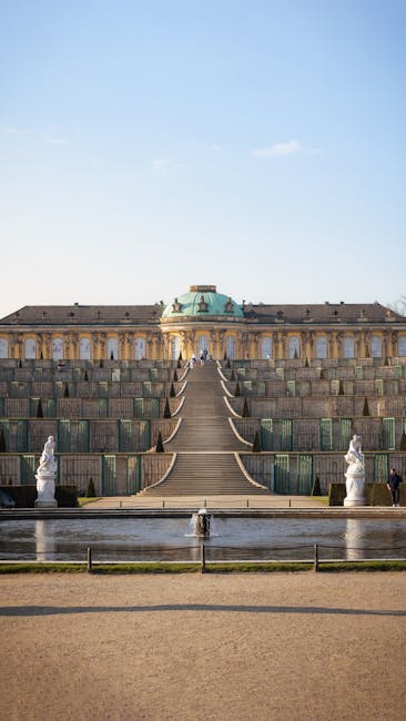 A breathtaking view of Sanssouci Palace's grand staircase and fountain under a clear blue sky.